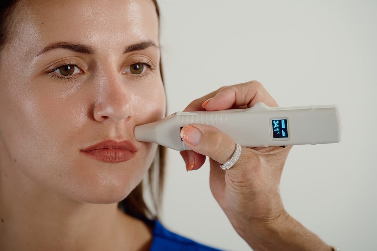 A practitioner taking a reading on the patient's cheek